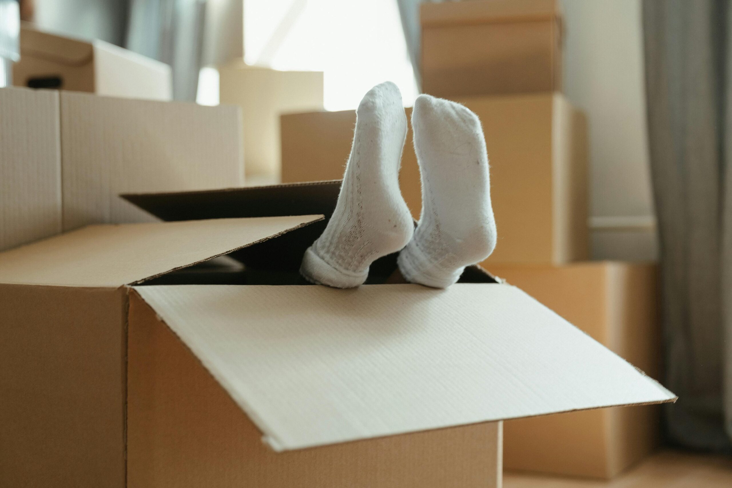 A playful moment during moving into a new home, with feet in a box and cardboard surroundings.