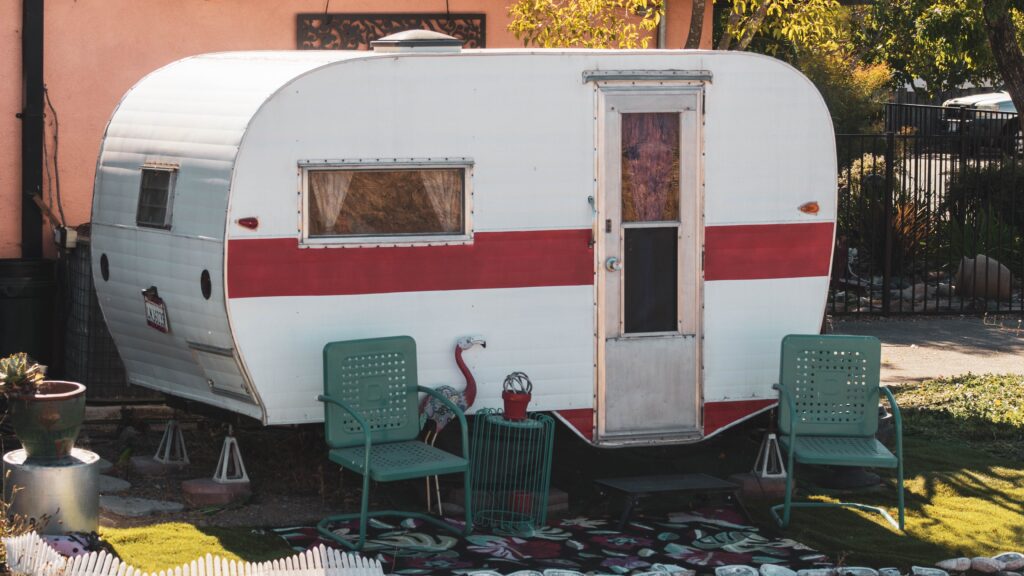 Charming vintage camper with chairs creating a cozy outdoor setting in sunlit garden.